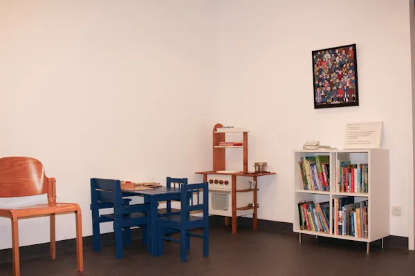 Kleine, helle Kinderspielecke mit vielen Bücher und einer Puppenküche.