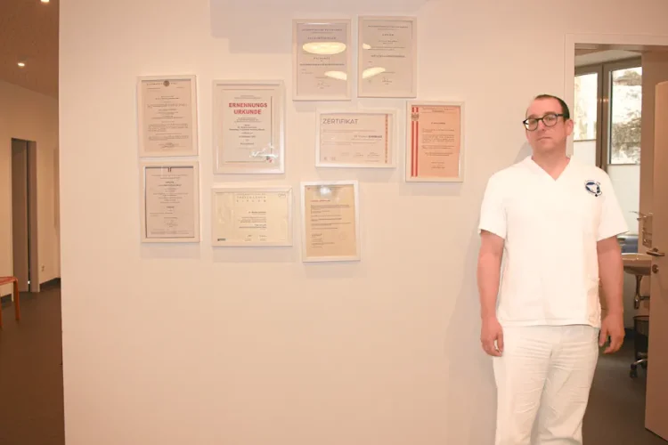 Dr. med. univ. Markus Zambisi neben seinen 9 Auszeichnungen